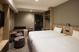 a hotel room with a large bed and a chair at the b namba-kuromon in Osaka