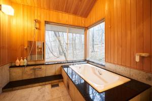 baño con bañera grande y ventana en S-villa Nasu Blanca, en Nasu