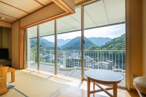 a living room with a large window with a view at Yumoto Fujiya Hotel in Hakone