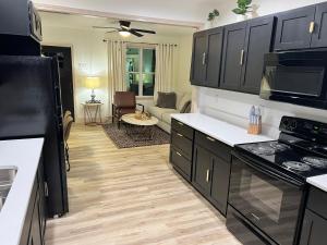 a kitchen with black cabinets and a living room at Modern 2 Bedroom Apartment in Monroeville