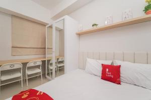 Un dormitorio con una cama con una almohada roja. en RedLiving Apartemen Transpark Juanda - Frams Properti Tower Jade with Netflix, en Bekasi