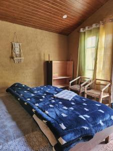 a bedroom with a blue comforter on a bed at Monkey Mud House and Camps, Bir in Bīr