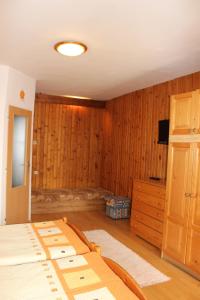 a bedroom with wooden walls and a bed and a television at Penzión Mária in Smižany