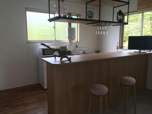 a kitchen with a counter with stools and a counter top at 大自然の一軒家。便利社会からの逃避、究極のセルフ山小屋ライフ in Madarao Kogen