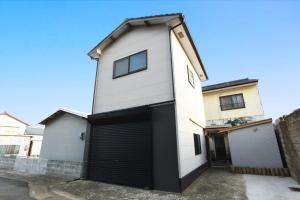 une maison blanche avec un grand garage dans l'établissement 一棟貸し平戸俺んち, à Hirado