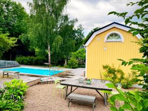 um edifício amarelo com uma mesa e uma piscina em Charming little country house in central Älmhult em Älmhult