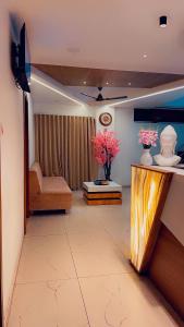 a living room with a television and a couch and flowers at HOTEL VENUS in Veraval