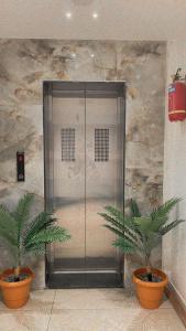 a metal elevator in a lobby with two plants at HOTEL VENUS in Veraval