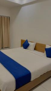 a bedroom with a large bed with blue pillows at HOTEL VENUS in Veraval
