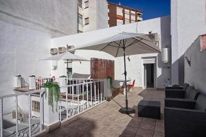 a patio with two umbrellas and a table and chairs at Apartamentos Gladiador in Mérida