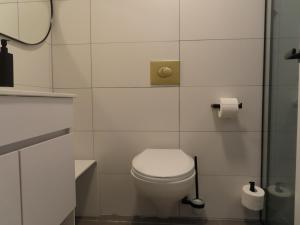 een witte badkamer met een toilet en een spiegel bij White Moon Inn in Jeruzalem
