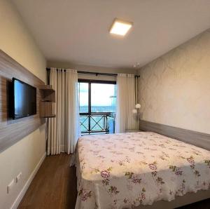 um quarto com uma cama, uma televisão e uma janela em Flat com Churrasqueira Monte castelo em Bezerros