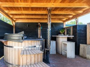 an outdoor kitchen with a wooden roof and a grill at Cosy forest cabin with a barrel sauna in Voorthuizen