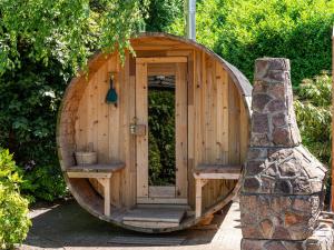 una sauna de madera con puerta de madera y 2 bancos en Cosy forest cabin with a barrel sauna, en Voorthuizen