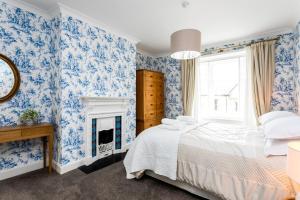 a blue and white bedroom with a bed and a fireplace at Westhill House in Warkworth