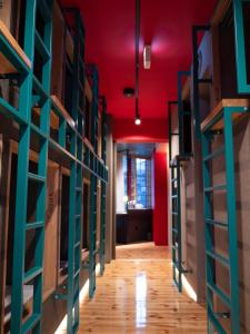 a hallway with red ceilings and racks of books at ELE Cabin Shinjuku Kabukicho in Tokyo