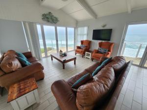 a living room with leather furniture and a view of the ocean at Seaside Tresure. in Mossel Bay