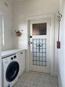 a laundry room with a washing machine and a door at ‘Lynton-Sur-Mer’ - Beachside Apt with Heating in Melbourne