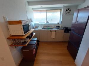 a kitchen with a microwave and a refrigerator at ゲストハウス　tonari in Inokuchi