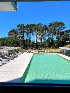 a swimming pool on a building with chairs and trees at Moderno Apartamento #1 Excelente ubicación in Punta del Este