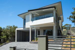 una gran casa blanca con una valla delante en Lilys at Hyams, en Hyams Beach