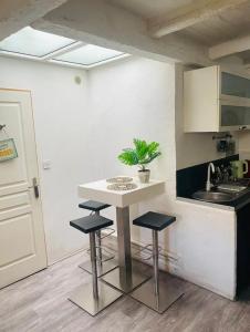 uma cozinha com uma mesa e dois bancos e um lavatório em Bienvenue chez vous au Panier ! Appartement classé 1 étoile em Marselha