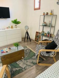uma sala de estar com uma cadeira, uma mesa e uma televisão em Bienvenue chez vous au Panier ! Appartement classé 1 étoile em Marselha