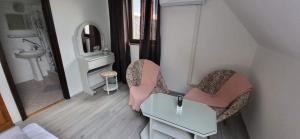 a bathroom with two chairs and a table and a mirror at Aniiza apartman in Örvényes