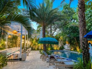 a pool with chairs and umbrellas and palm trees at The Bali Dream Villa & Resort Echo Beach Canggu in Canggu