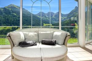 a white couch in front of a large window with mountains at Hotel Leitner in Mittelberg