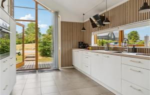 StubbekøbingにあるAmazing Home In Stubbekøbingの白いキャビネットと大きな窓のあるキッチン
