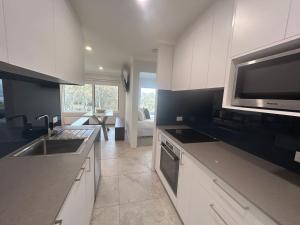 a kitchen with white cabinets and a sink and a microwave at House Matterhorn in Jindabyne