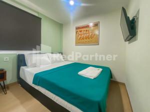 een slaapkamer met een blauw bed en een televisie bij Mamifokobo Guesthouse Puncak Mitra RedDoorz in Ciloto