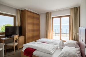 VeranoにあるHotel Oberwirtのベッド2台、デスク、テレビが備わるホテルルームです。