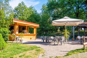 ein Restaurant mit einem Sonnenschirm, Tischen und Stühlen in der Unterkunft Camping de la Bucherie in Saint-Saud-Lacoussière
