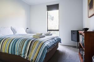 a bedroom with a bed with a striped blanket and a window at Modern family friendly getaway in Dunedin