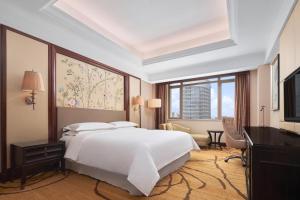 a bedroom with a white bed and a large window at Sheraton Shantou Hotel in Shantou