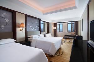 een hotelkamer met drie bedden en een flatscreen-tv bij Sheraton Shantou Hotel in Shantou