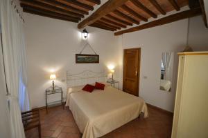 um quarto com uma cama branca e almofadas vermelhas em Il Palazzetto em Montepulciano