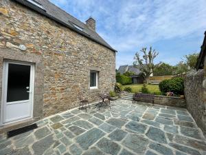 a stone house with a stone patio with a white door at La Maisonnette in Les Pieux