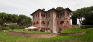 ein großes Backsteinhaus auf einem Grasfeld in der Unterkunft San Bartolomeo Suite in Castel Rigone