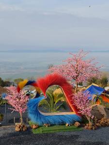 una escultura de un pájaro con plumas y árboles coloridos en The Cloud View วิวเหนือเมฆแคมป์ ที่พักวิวสวยเขายายเที่ยง, en Ban Wang Sai