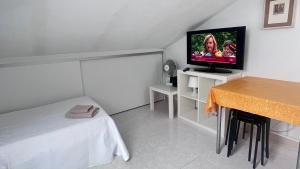 mały pokój z łóżkiem i telewizorem z płaskim ekranem w obiekcie apartamento abuhardillado w mieście Cuchia