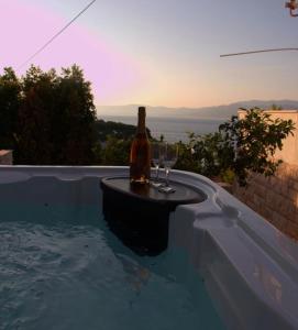 uma garrafa de vinho e dois copos numa piscina em Seaview Residence em Splitska
