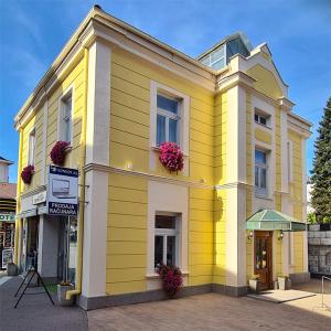 a yellow building with flowers in the window at KONDOR apartmani in Vrnjačka Banja