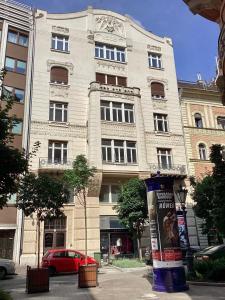 duży budynek z czerwonym samochodem przed nim w obiekcie Central Apartments of Budapest w Budapeszcie