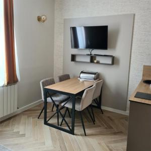 une table à manger avec des chaises et une télévision murale dans l'établissement KONDOR apartmani, à Vrnjačka Banja