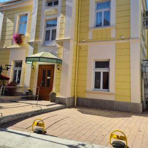 un bâtiment jaune avec deux barrières jaunes devant lui dans l'établissement KONDOR apartmani, à Vrnjačka Banja
