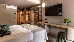 a bedroom with a bed and a desk and a tv at Hotel Terme Jezercica in Donja Stubica