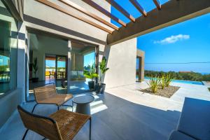 eine Terrasse mit Stühlen und Blick auf das Meer in der Unterkunft ISKIOS Premium in Agia Marina